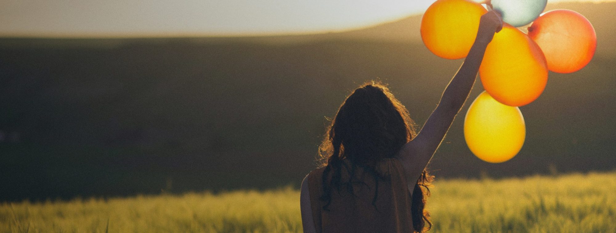 Woman holding baloons outside in the sunshine
